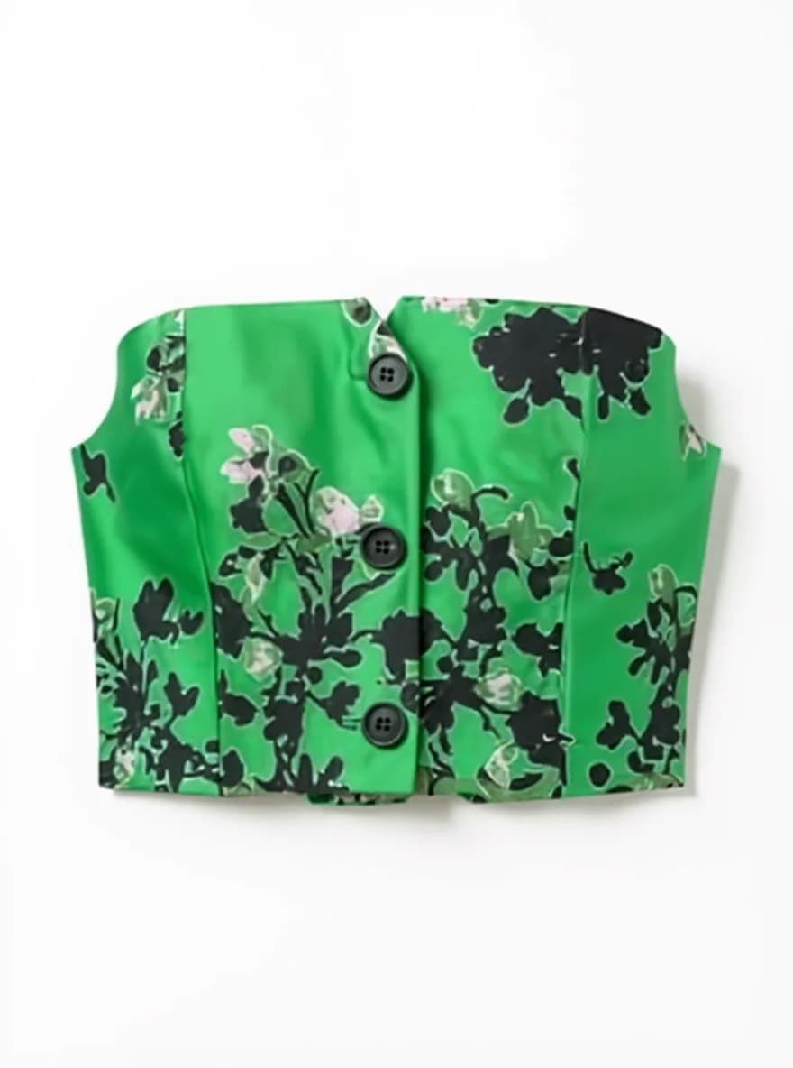 A cropped vest-style garment photographed against a white background. The garment features a vibrant kelly green base color with a black floral print pattern. The floral design consists of large abstract flower shapes and leaves scattered across the fabric. The garment has three black buttons down the front center. The construction shows clean lines with visible seams creating a structured silhouette. The garment is photographed flat and centered in the frame, with equal white space on all sides. The fabric has a smooth, matte finish typical of woven materials. The floral print pattern is bold and contemporary, with the black elements creating strong contrast against the bright green background.